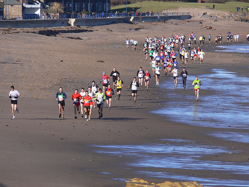 The field streching out along the beach with the famous red vests well to the fore